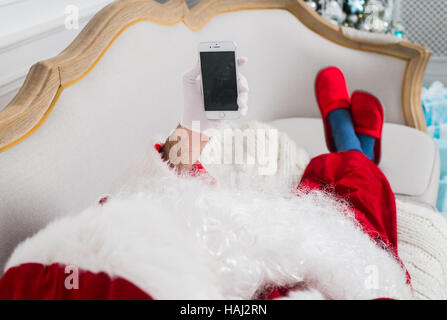 Santa claus using mobile phone at home during christmas time Stock Photo