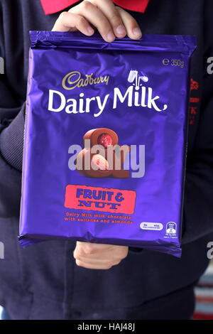 Close up of male child hand holding Cadbury chocolate fruits and nuts Stock Photo