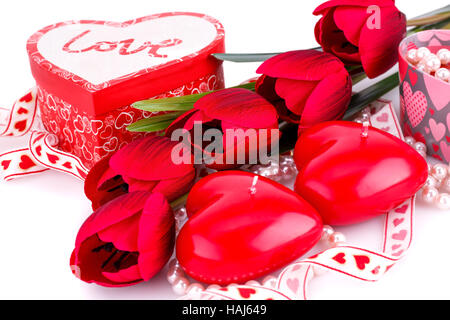 Red heart candles, tulips, necklaces and gift boxes on white background. Stock Photo