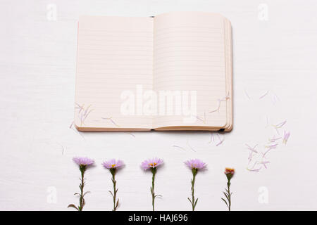 notes and flowers on a white background.The composition of the notebook and purple chrysanthemumst. Top view, flat Stock Photo