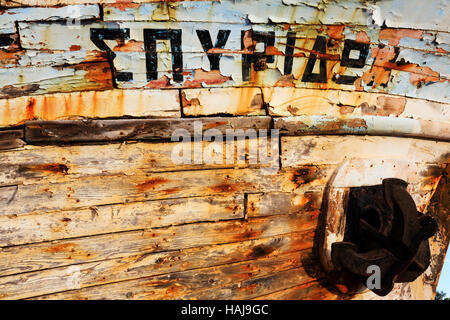 Detail of greek name and peeling, faded paint on old, beached boat. Latsi, Polis,Cyprus Stock Photo