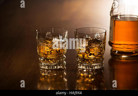 Whiskey with ice in glasses, rustic wood background. Stock Photo