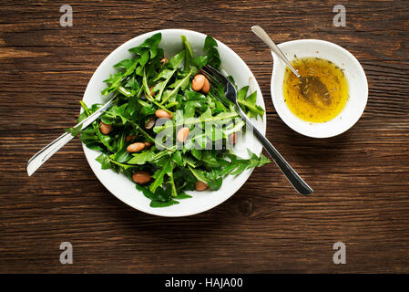Fresh dandelion salad with beans on wooden background Stock Photo