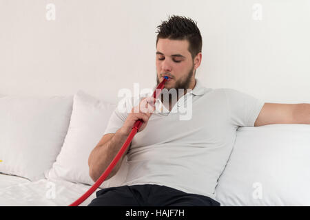 Young Man Smoking Shisha At Arabic Restaurant - Man Exhaling Smoke Inhaling From A Hookah Stock Photo
