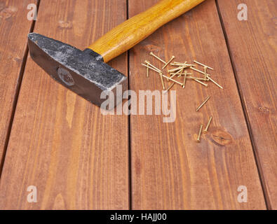 Big hammer with pile of metal nails on wooden surface Stock Photo