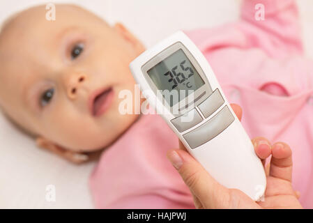 Measuring baby's temperature with contactless thermometer Stock Photo