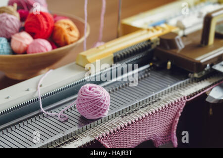 Hand Knitting Machine. A knitting machine is a device used to create knitted fabrics in a semi or fully automated fashion. Stock Photo