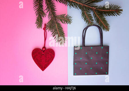 Xmas composition. Shopping bag hanging on the christmas tree twigs as decoration. Colourful background. Shop, sale and gifts concept. Top view. Flat lay Stock Photo