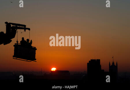 Construction workers watch the sun set over London, as today marks the start of the meteorological winter. Stock Photo