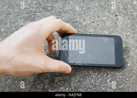 hand pick up the mobile phone with broken display Stock Photo