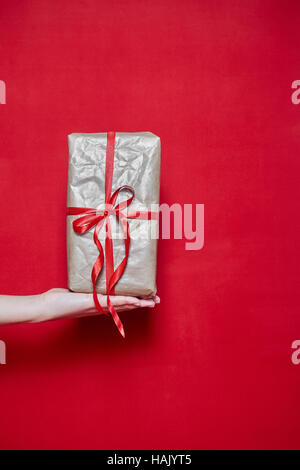 Womans Hand holding a box gift on red background Stock Photo