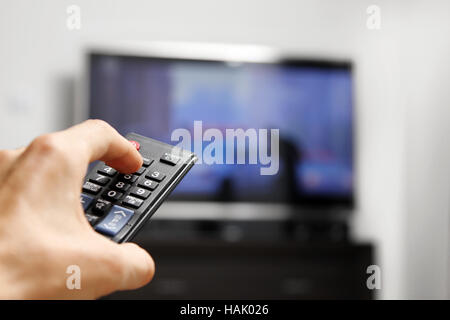 hand hold remote control in front of tv Stock Photo
