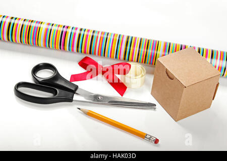 Gift wrapping. Wrapping paper, tape and gift box on a light wooden