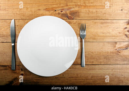 empty white plate on brown wooden table Stock Photo