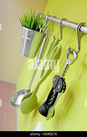 kitchen utensils hanging on green wall Stock Photo