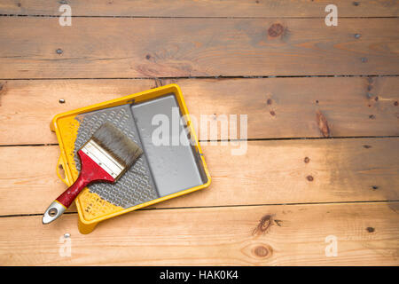 wooden plank floor varnishing. gray varnish and paintbrush in tray Stock Photo