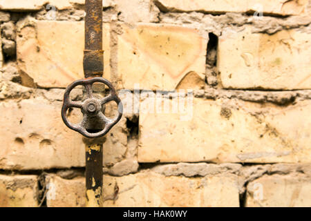 rusty pipeline valve on brick wall background Stock Photo