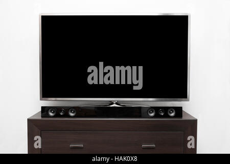 big tv with blank screen on brown commode at white wall Stock Photo