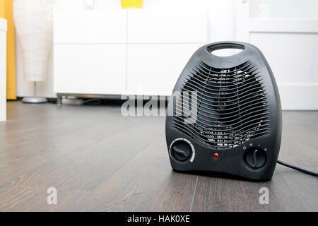 black electric heater on laminate floor in the room Stock Photo