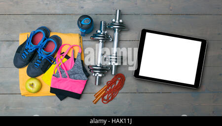 colorful fitness equipment and blank digital tablet on gym floor