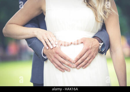 newlyweds - heart shaped men's hands on woman's belly Stock Photo