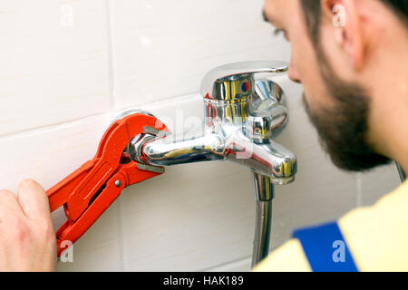 plumber installing water tap in bathroom Stock Photo