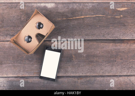 cardboard virtual reality glasses with blank smartphone on wooden background Stock Photo