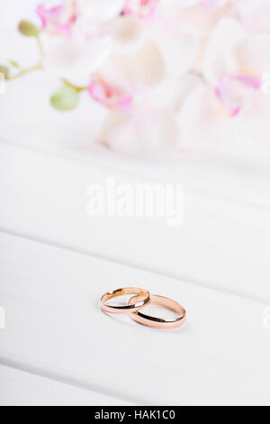 golden wedding rings with flowers on white wooden table Stock Photo