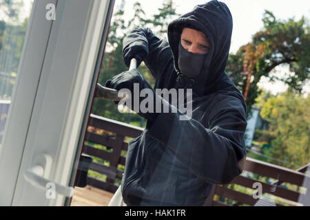 house robbery - burglar opens balcony doors with crowbar Stock Photo