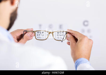 optician holds glasses in front of eyesight test chart Stock Photo
