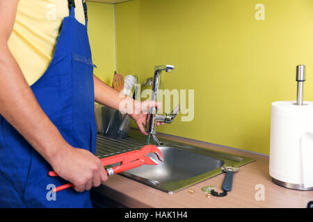 plumber working in domestic kitchen, repairing faucet Stock Photo