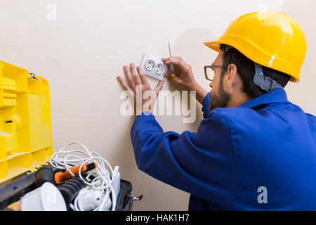 electrician installing wall socket Stock Photo