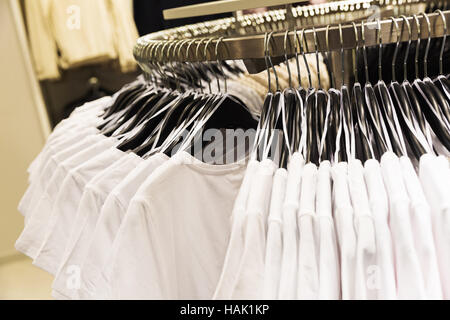 white t-shirts hanging on rack in a store Stock Photo