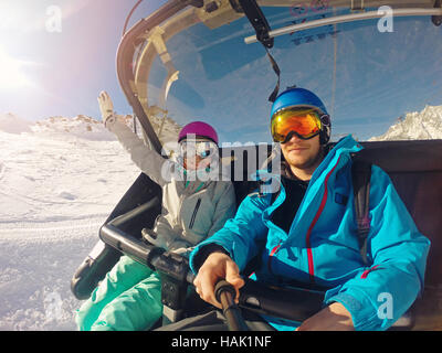 happy couple taking selfie in chairlift at ski resort Stock Photo