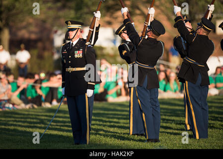 US Army Drill Team Precision Drill Routine Arlington Virginia | ARLINGTON, Virginia — Soldiers of the U.S. Army Drill Team raise bayonet-tipped rifles overhead in a synchronized routine during the Twilight Tattoo at Joint Base Myer-Henderson Hall. The team, part of the 3d U.S. Infantry Regiment's 4th Battalion, performs with 1903 Springfield rifles weighing about 8.5 pounds (3.9 kg) each. The pageant runs weekly at Summerall Field, the same parade ground where cavalry drills once drew crowds before World War II. Stock Photo