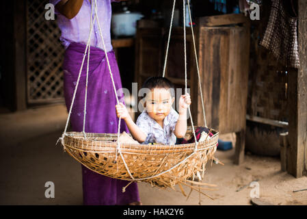 MINNANTHU, Myanmar — A small child swings in a woven basket in Minnanthu Village in Bagan, Myanmar. Set amidst the archeological ruins of the Plain of Bagan, the tiny Minnanthu Village retains the traditional way of life. Stock Photo