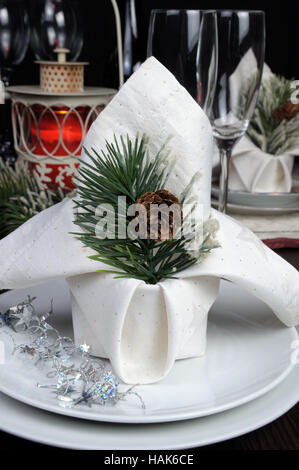 A fragment of a Christmas table setting napkin decorated with pine branches pinecone Stock Photo