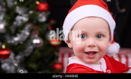 Baby boy smiling cheerfully at camera in santa clause outfit Stock Photo