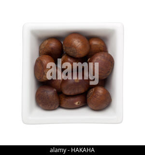 Roasted chestnuts in a square bowl isolated on white background Stock Photo