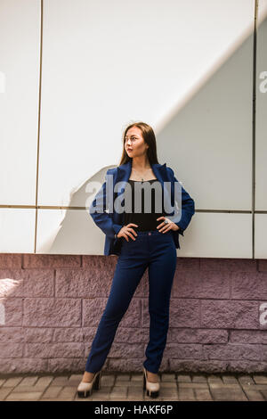 Beautiful asian girl in fashion style wearing blue suit, full length portrait, over light and shadow line background. Business woman look at dark side Stock Photo