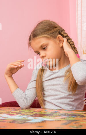 Girl thinks collecting picture of puzzles Stock Photo
