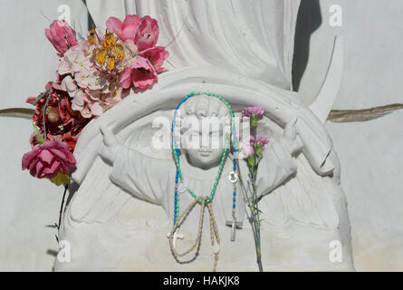 Close up of baby Jesus grave memorial with artificial flowers and rosaries Stock Photo