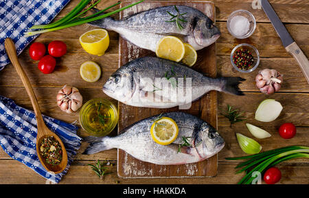 Fresh fish with herbs, spices and vegetables on rustic wooden background. Healthy food concept. Top view Stock Photo