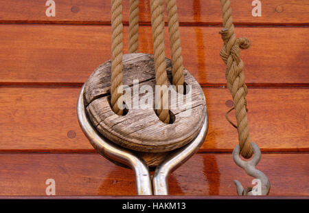 Close-up of a rope with a knotted end tied around a cleat on a wooden pier/ Nautical rope Stock Photo
