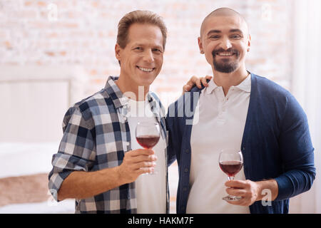 Smiling non-traditional couple drinking wine at home Stock Photo