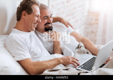 Happy gay couple using the laptop and hugging Stock Photo