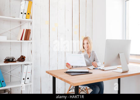 Beautiful business young woman working with papers and computer in office Stock Photo