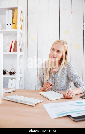 Portrait of a thoughtful blonde business woman making notes and looking away Stock Photo