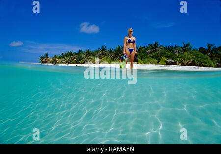 Half underwater half over water picture of a 20 year-old woman walking from an island to go snorkeling, Summer Island Village Stock Photo