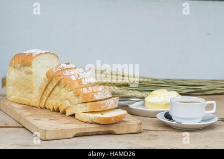 Bread on chopping wood and black coffee and butter on wood table. Stock Photo